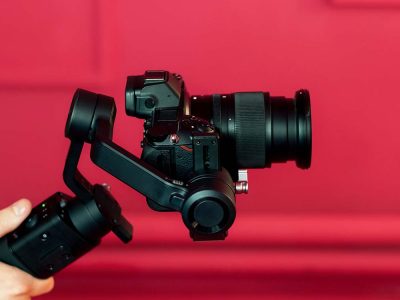 Photographer holding a professional camera on a stabilizer in a studio with red walls